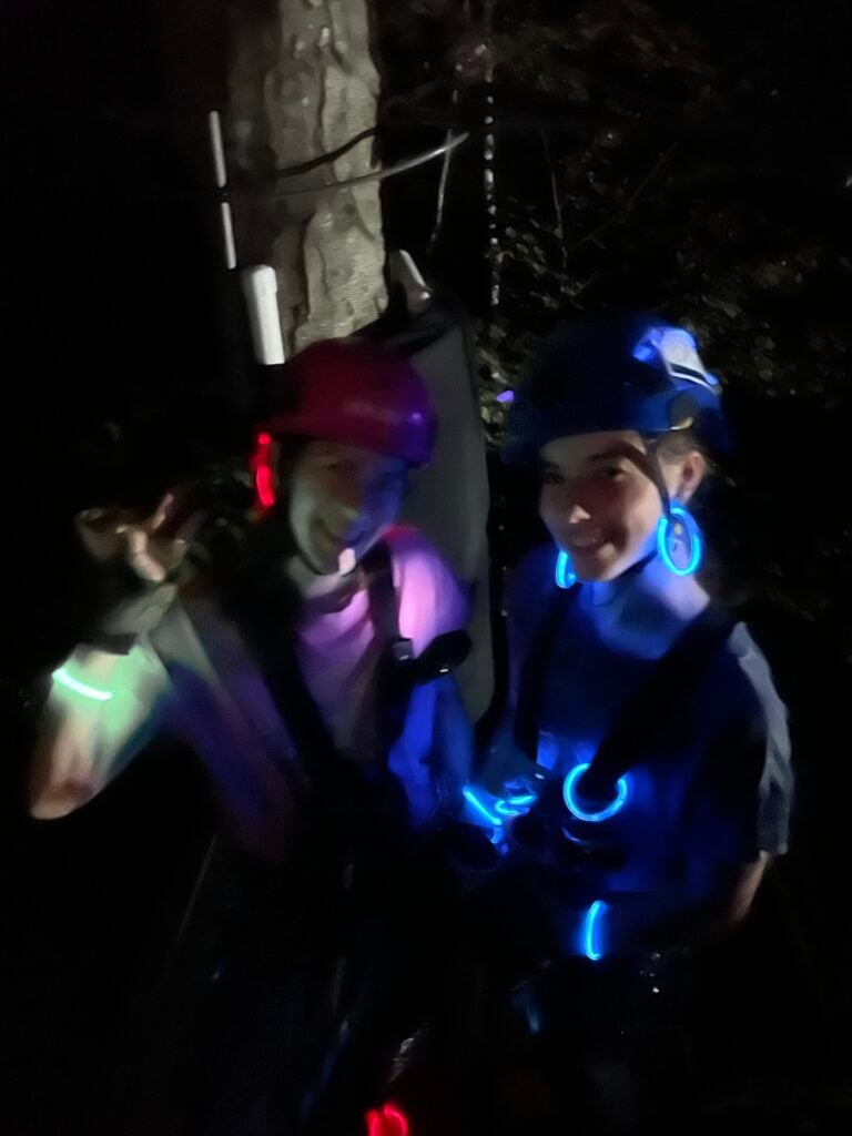 Two guests laughing together in the dark, lit by glow necklaces and bracelets