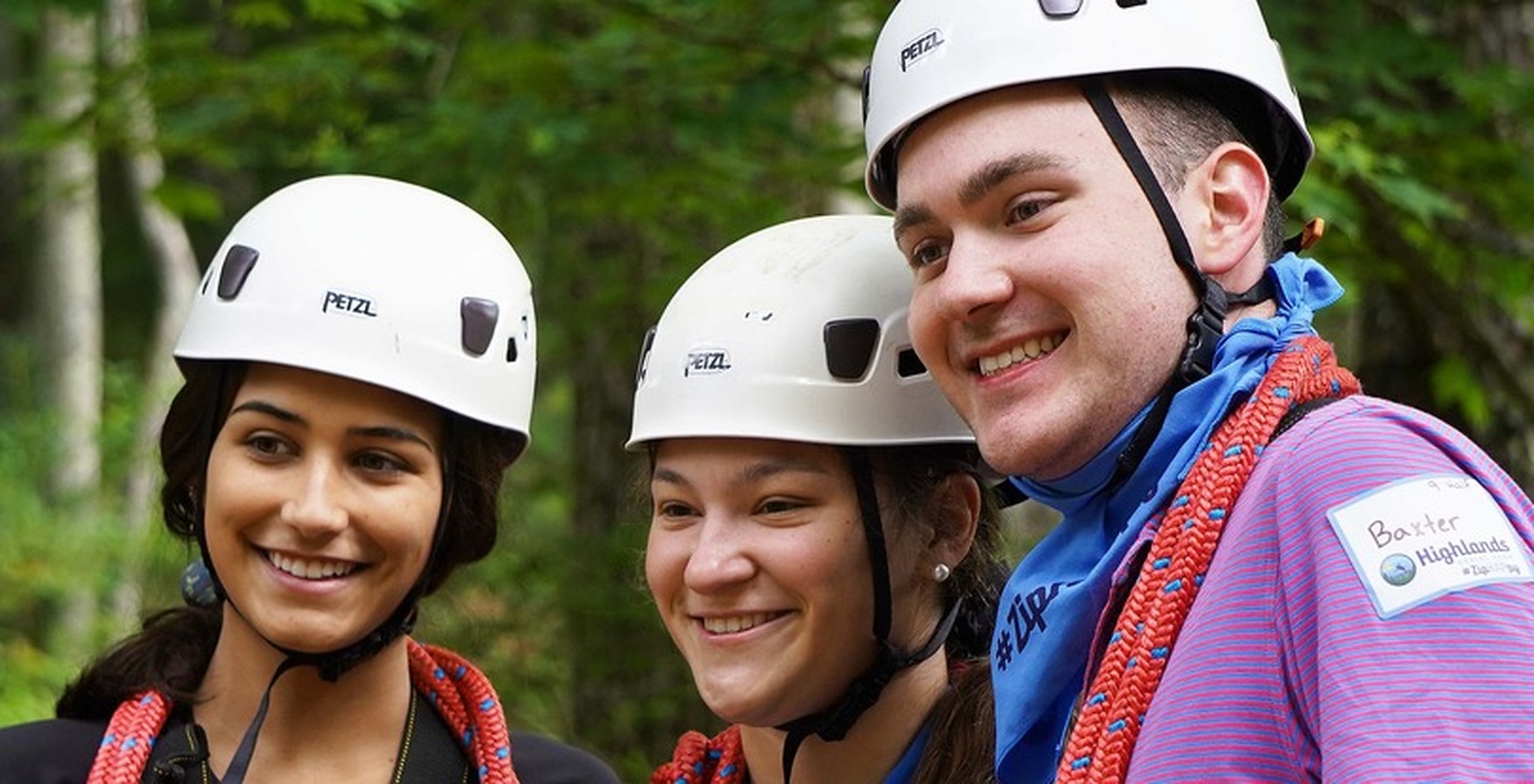 Three adults in zipline helmets smiling together