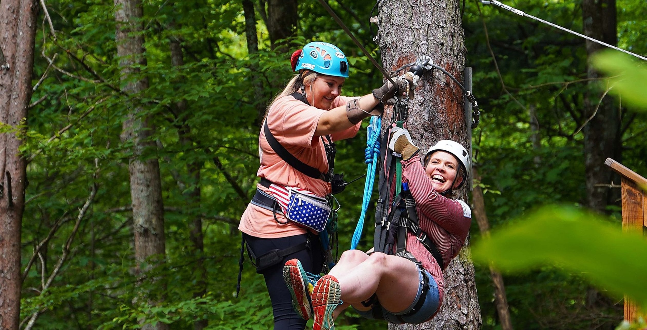 Two adults laughing on a treetop platform