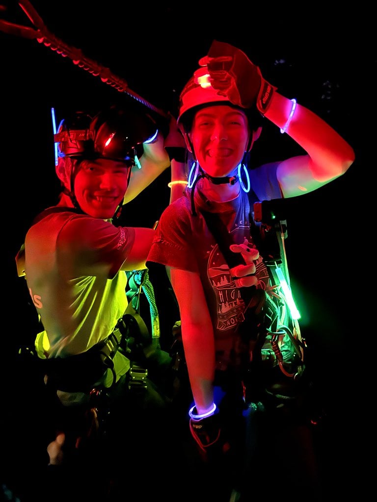 Two guests laughing in helmets and glow bracelets
